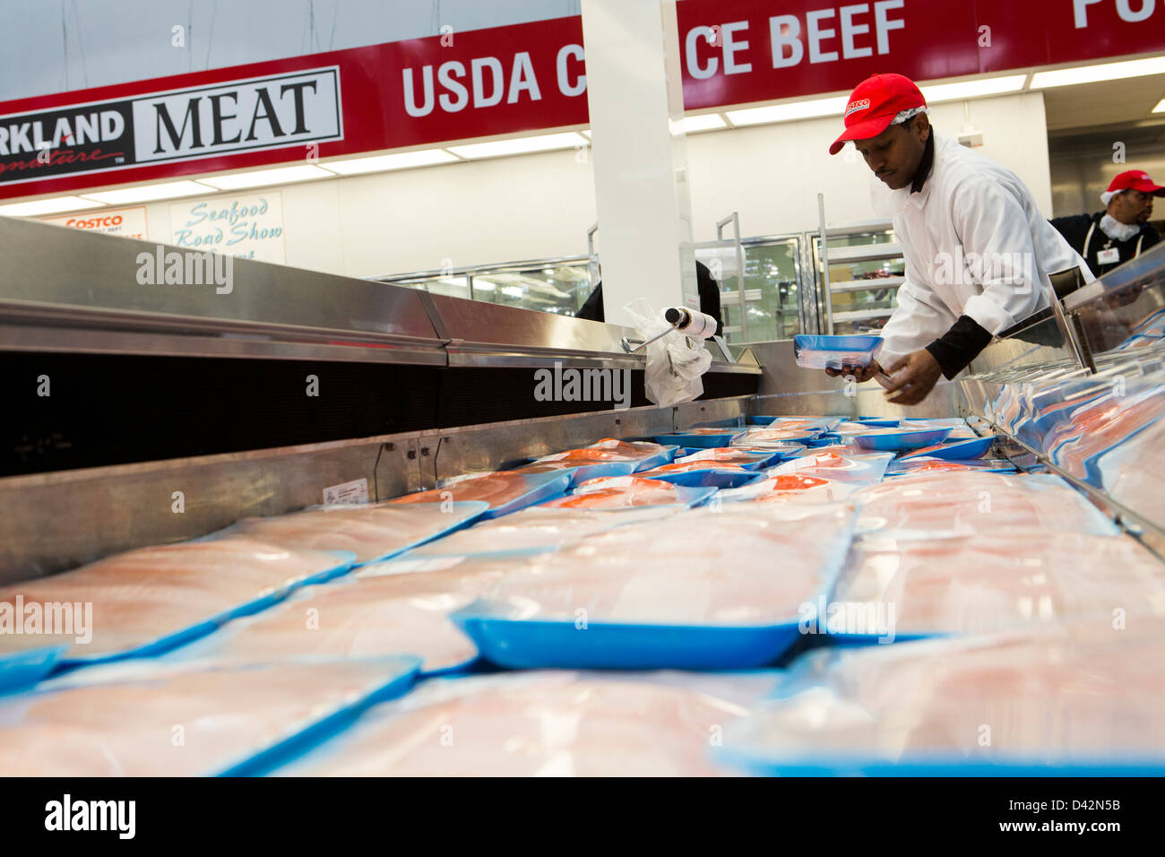 A Costco employee stocking salmon fillets at a Costco Wholesale