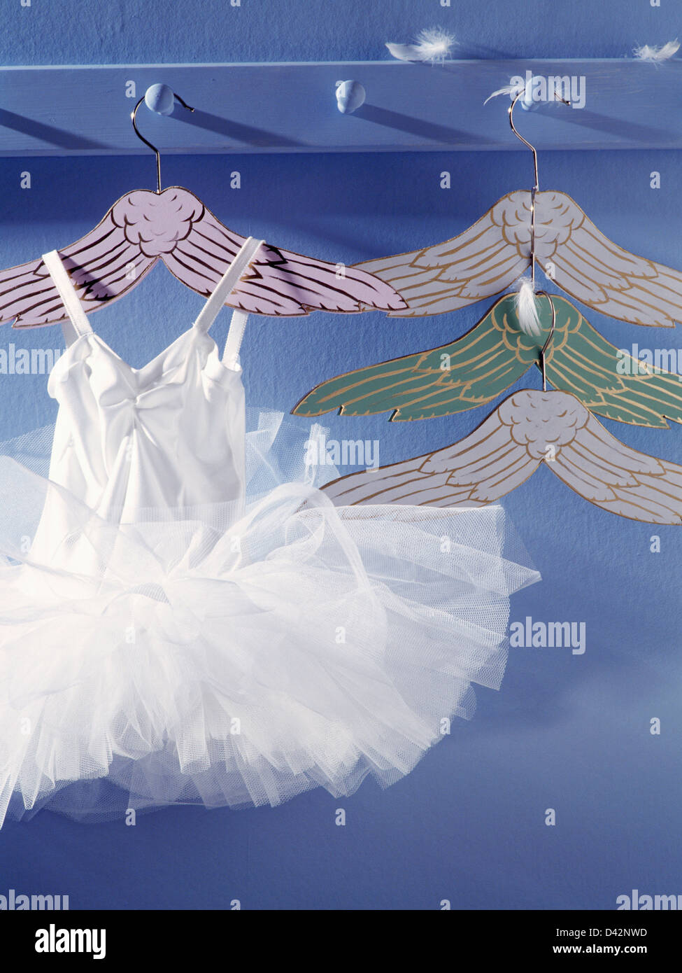 Closeup of peg rail with child's white ballet dress on white angel's