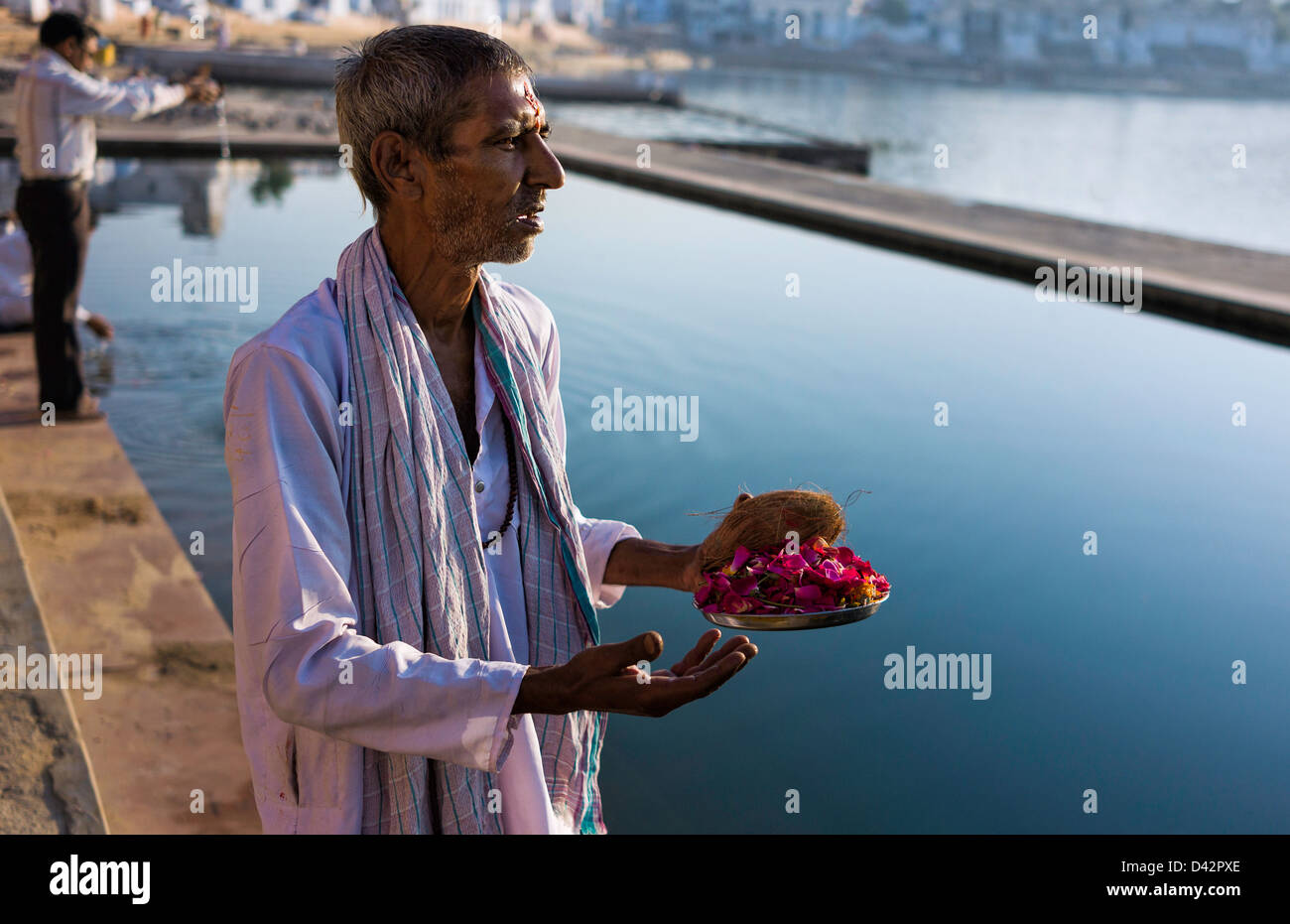Hindu Brahmin priest offers votive offerings and prayers to the Sun God at the holy lake in Pushkar, Rajasthan, India. Stock Photo