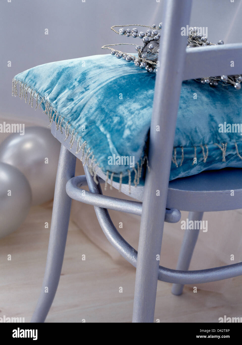 Close-up of turquoise chenille velvet cushion on silver painted chair Stock Photo