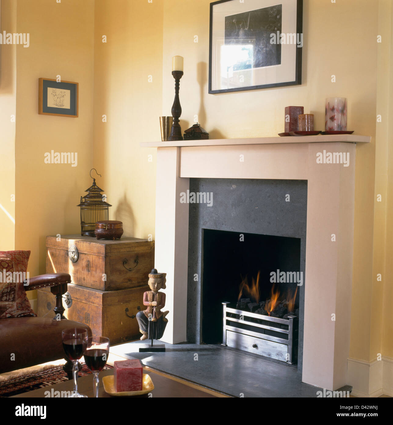 Fire burning in grate in traditional living room with old wooden boxes in corner of room and