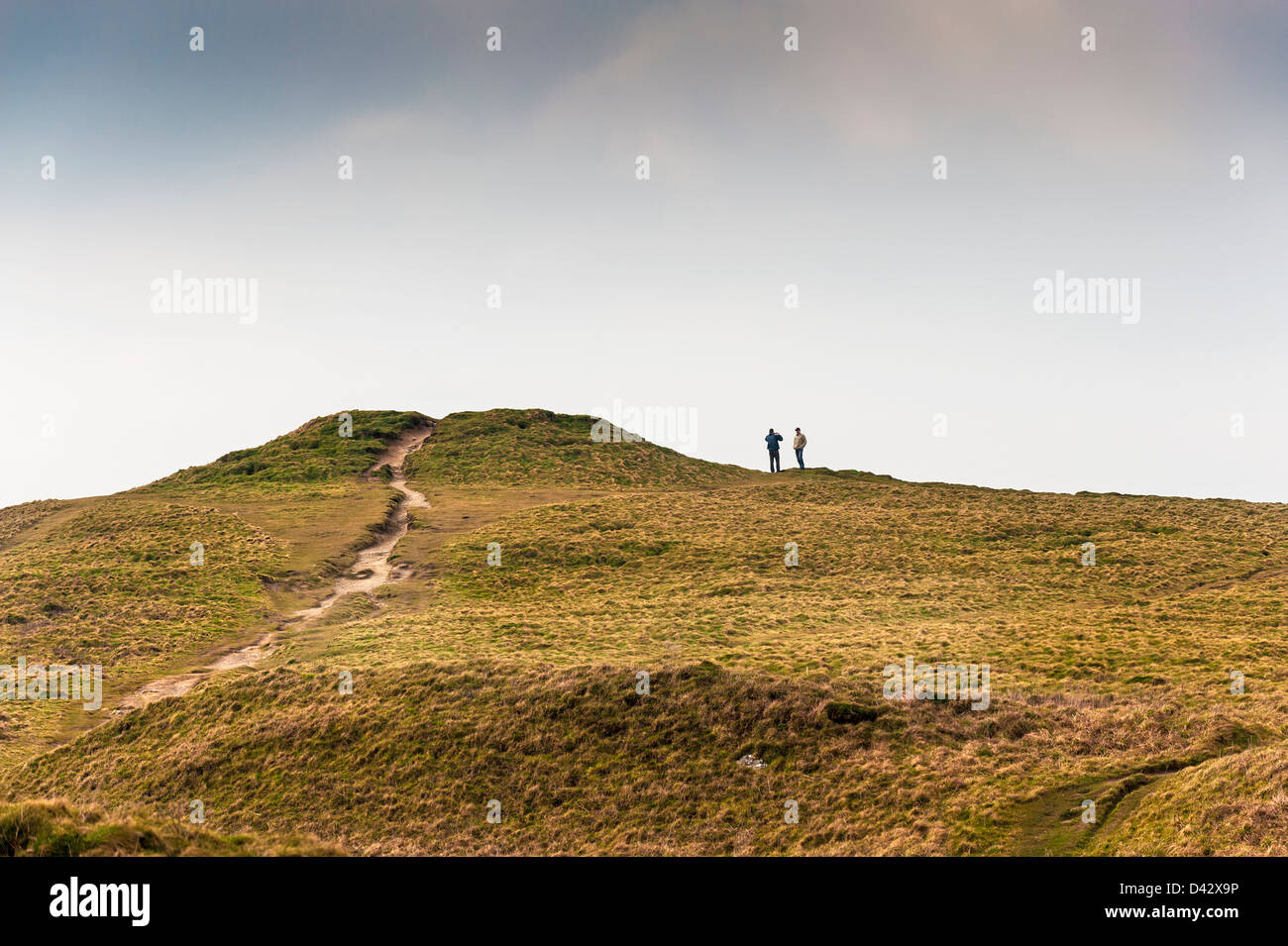 Tourists standing next to a the remains of a bronze age burial mound. Stock Photo