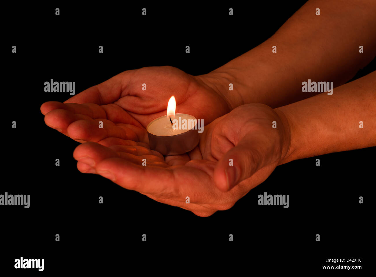 Candle in the hands over a black background Stock Photo