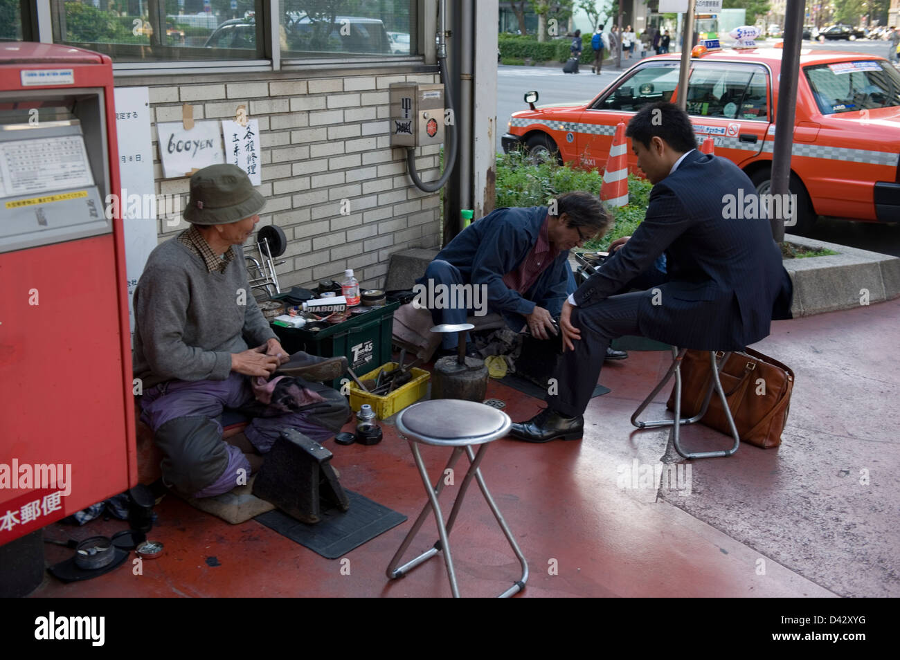 Sidewalk shoe shine and shoe repair service set up at the entry to Tokyo station. Stock Photo