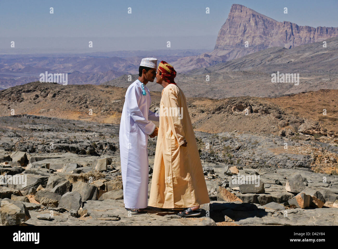 Omani men touching noses in greeting, Jebel Misht in background, Oman Stock Photo