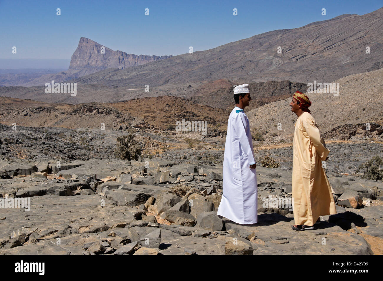 Omani men talking in rocky landscape near Nizwa, Oman Stock Photo