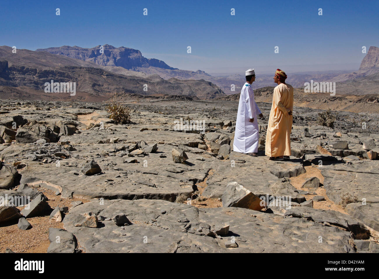 Omani men talking in rocky landscape near Nizwa, Oman Stock Photo
