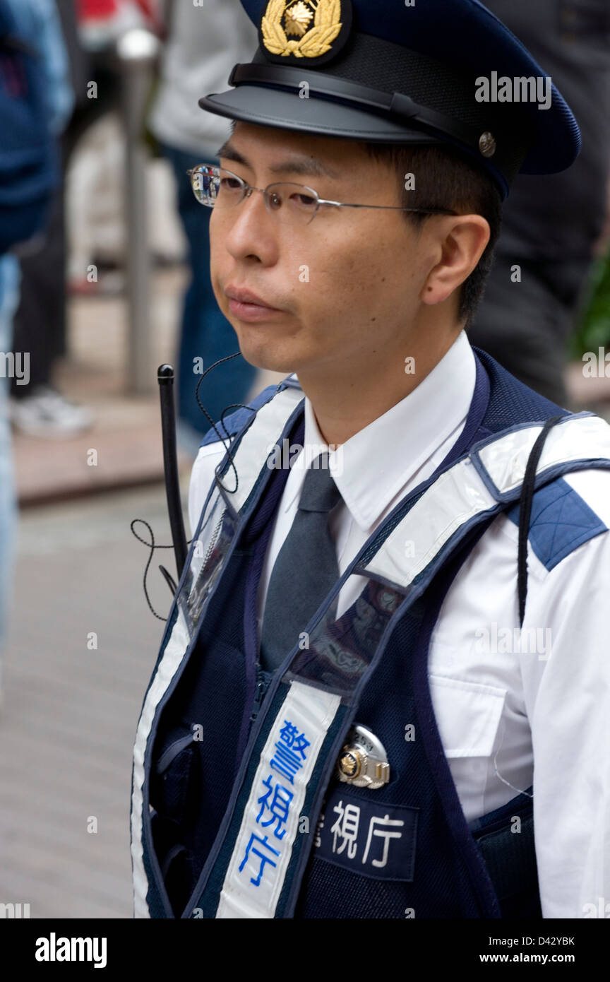 A Japanese policeman in uniform keeps a watch on activities around himself in Tokyo. Stock Photo