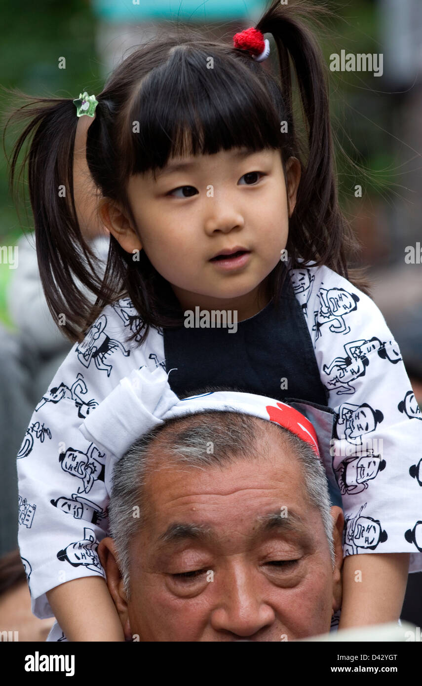 Grandfather carrying his granddaughter on his shoulders for a better view of Sanja Matsuri Festival in Tokyo Stock Photo