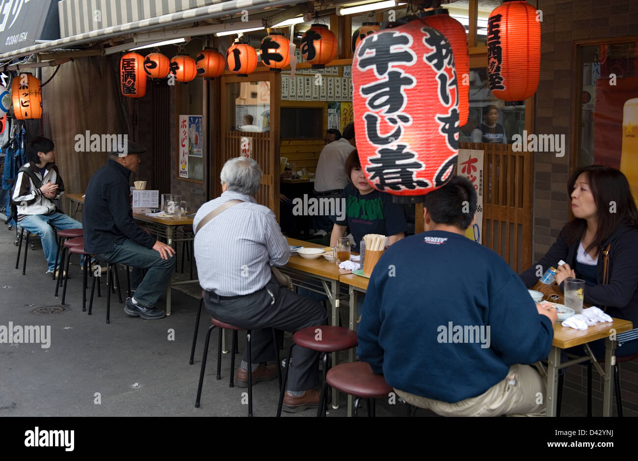 People stop for quick beer and small meal at street-side izakaya, or drinking establishment, in Asakusa, Tokyo. Stock Photo