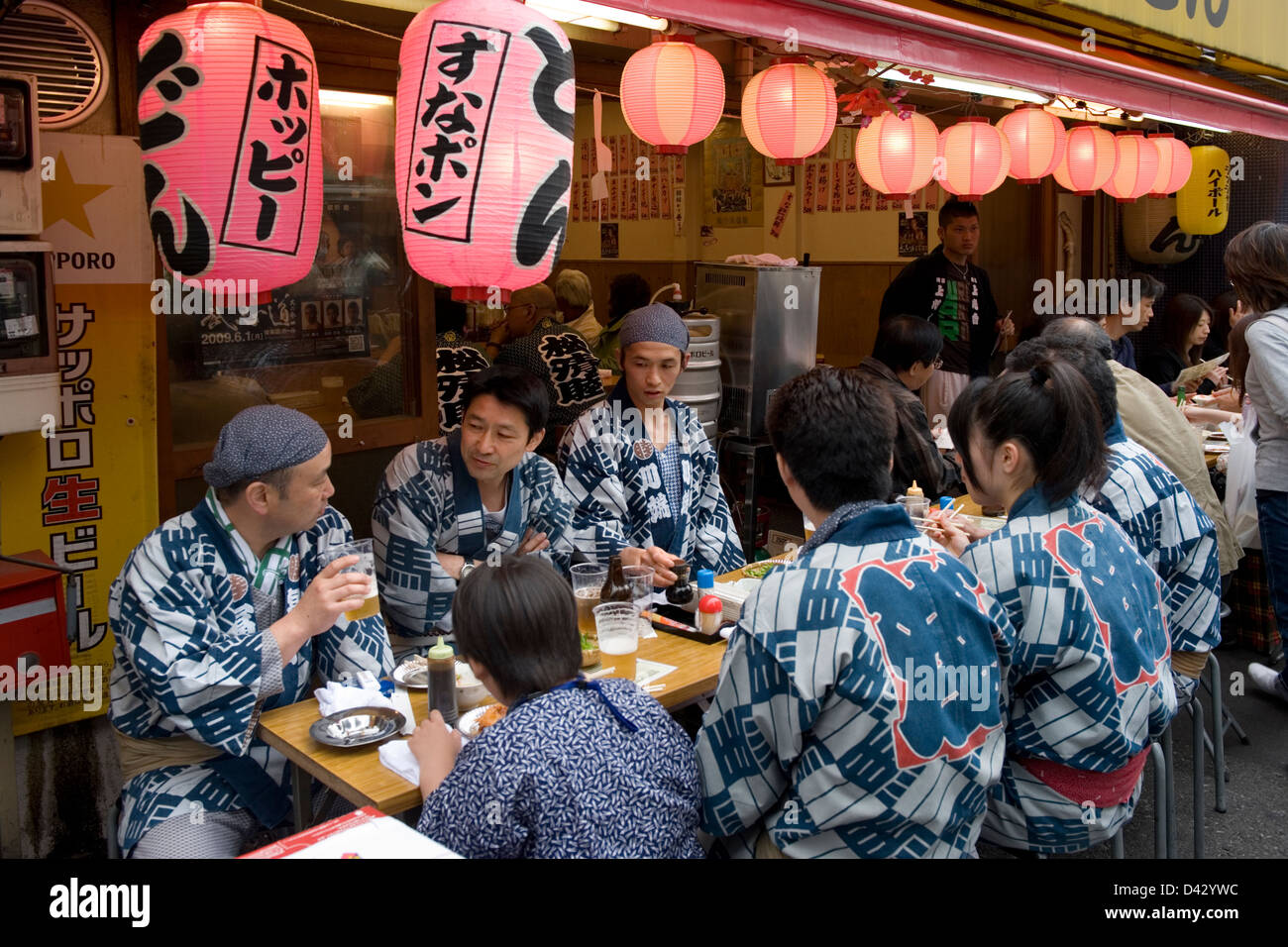 Group of festival participants stop for quick beer and small meal at street-side izakaya, or drinking establishment, in Tokyo. Stock Photo