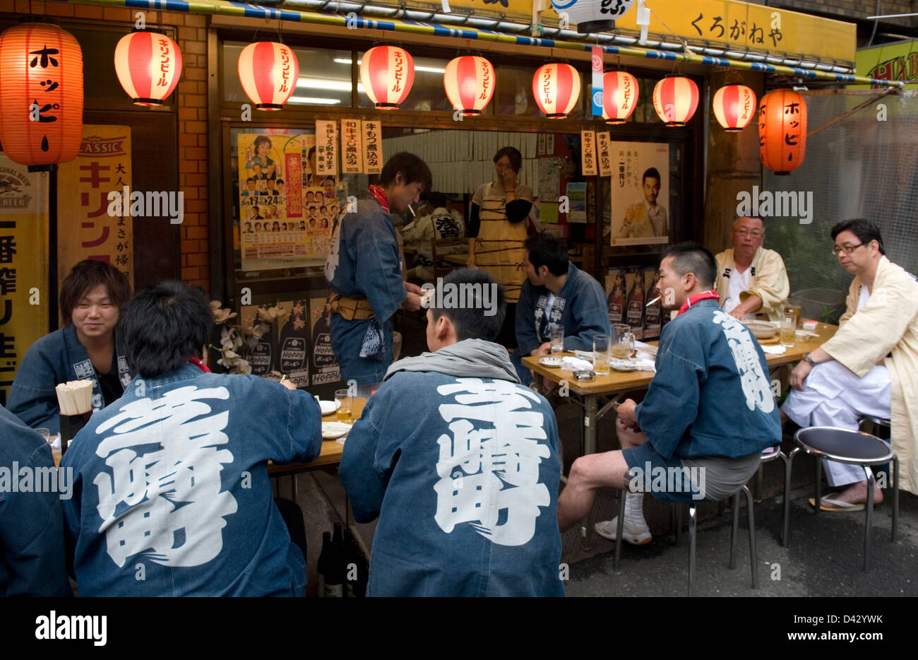 Group of festival participants stop for quick beer and small meal at street-side izakaya, or drinking establishment, in Tokyo. Stock Photo