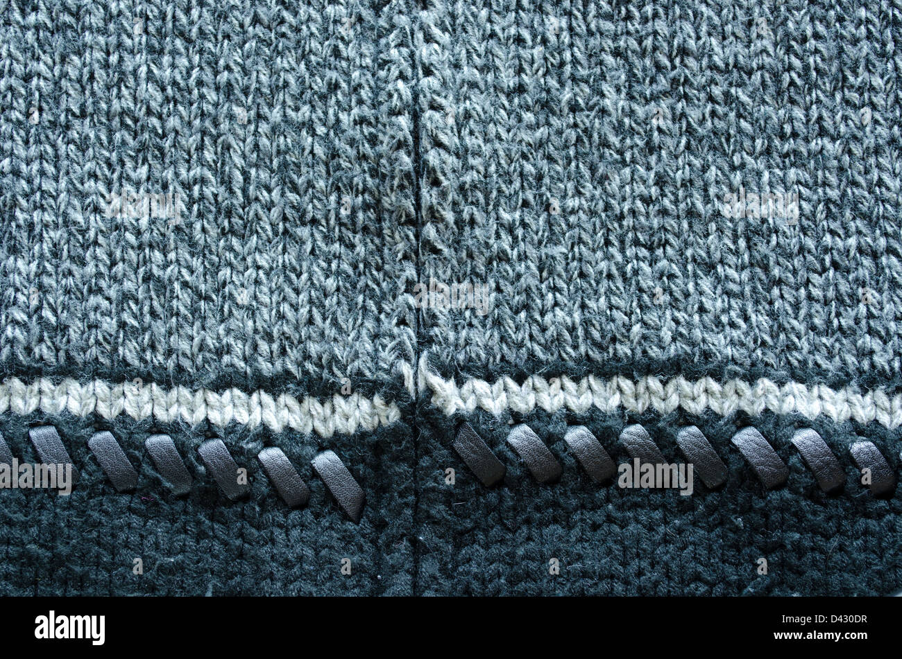 wool knit sweater texture decorated with leather stitch. white grey and black colors backdrop closeup Stock Photo