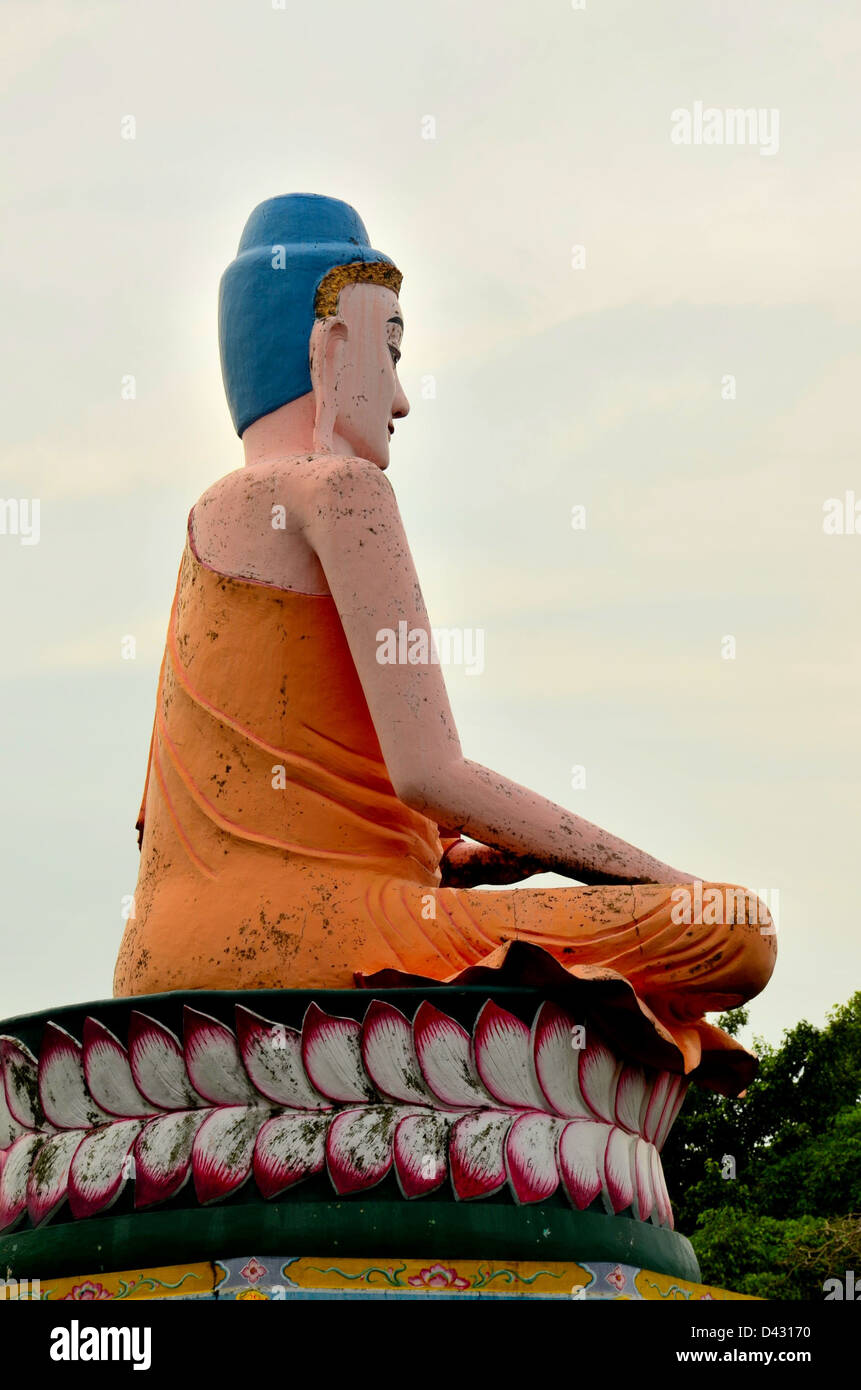 Meditating Buddha in lotus position seated on flower petals Stock Photo