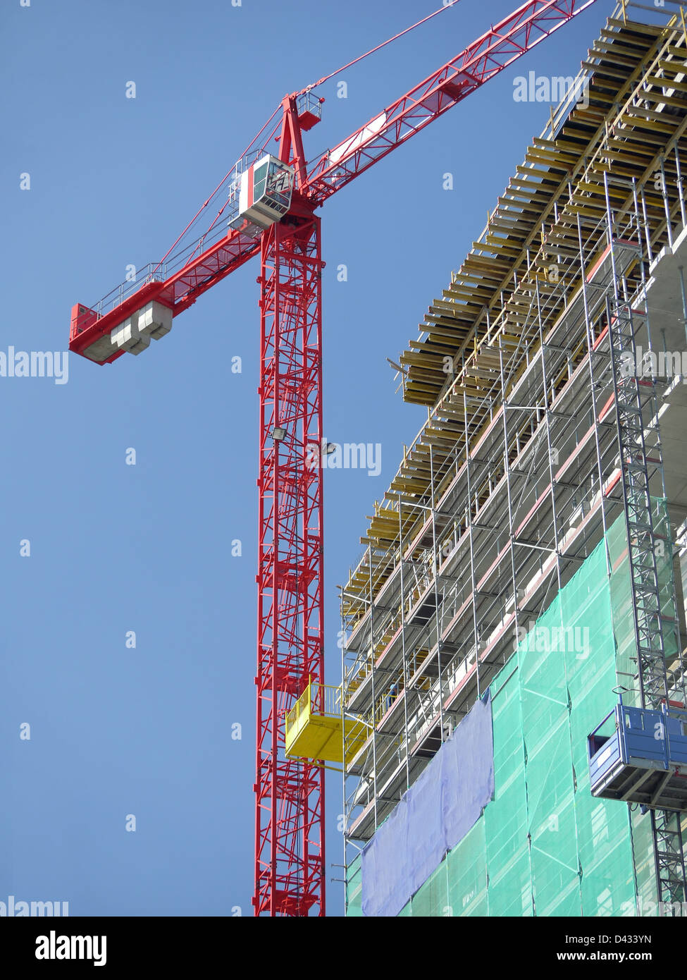 Raw state residential highrise and jib crane over clear blue sky Stock