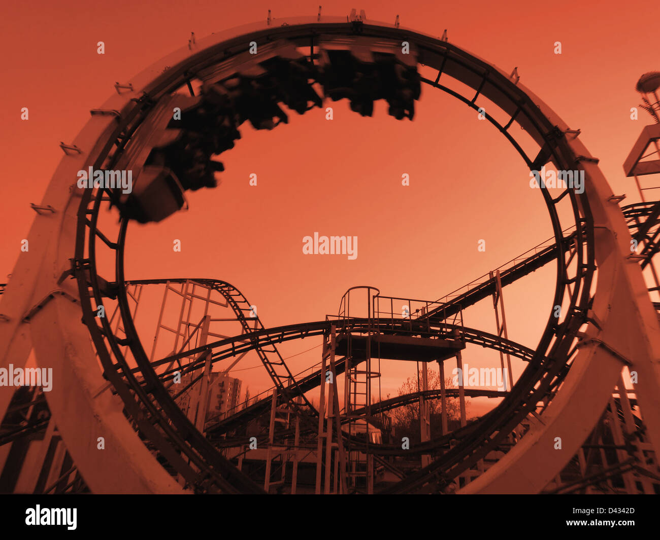Roller coaster train making the loop - shot against orange sky Stock Photo