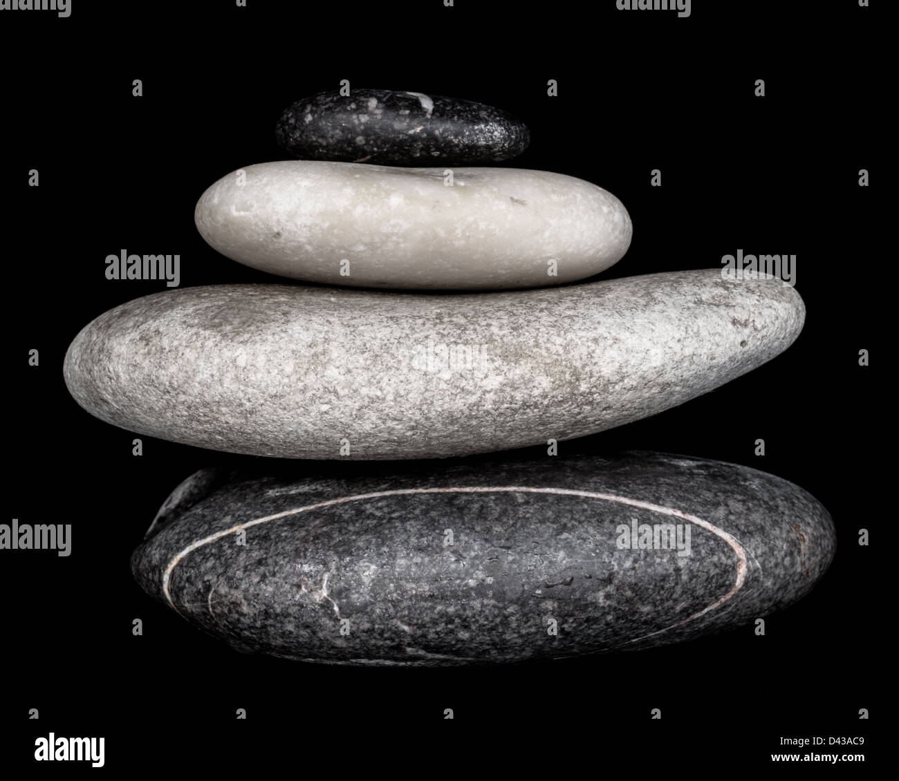 Black & White Close Up Image of a Stack of Four Pebbles on a Black Background. Stock Photo