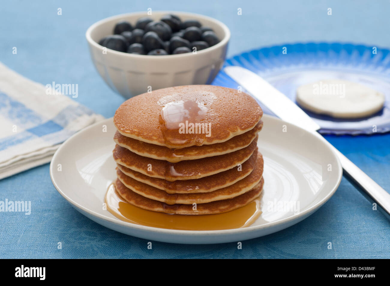 Close-up view of a stack of Pancakes with maple syrup. Butter and berries on the background. Stock Photo