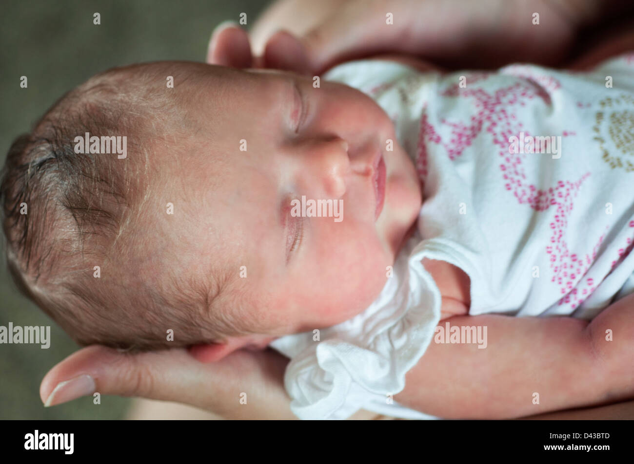 sleeping newborn infant baby girl being held by a woman Stock Photo