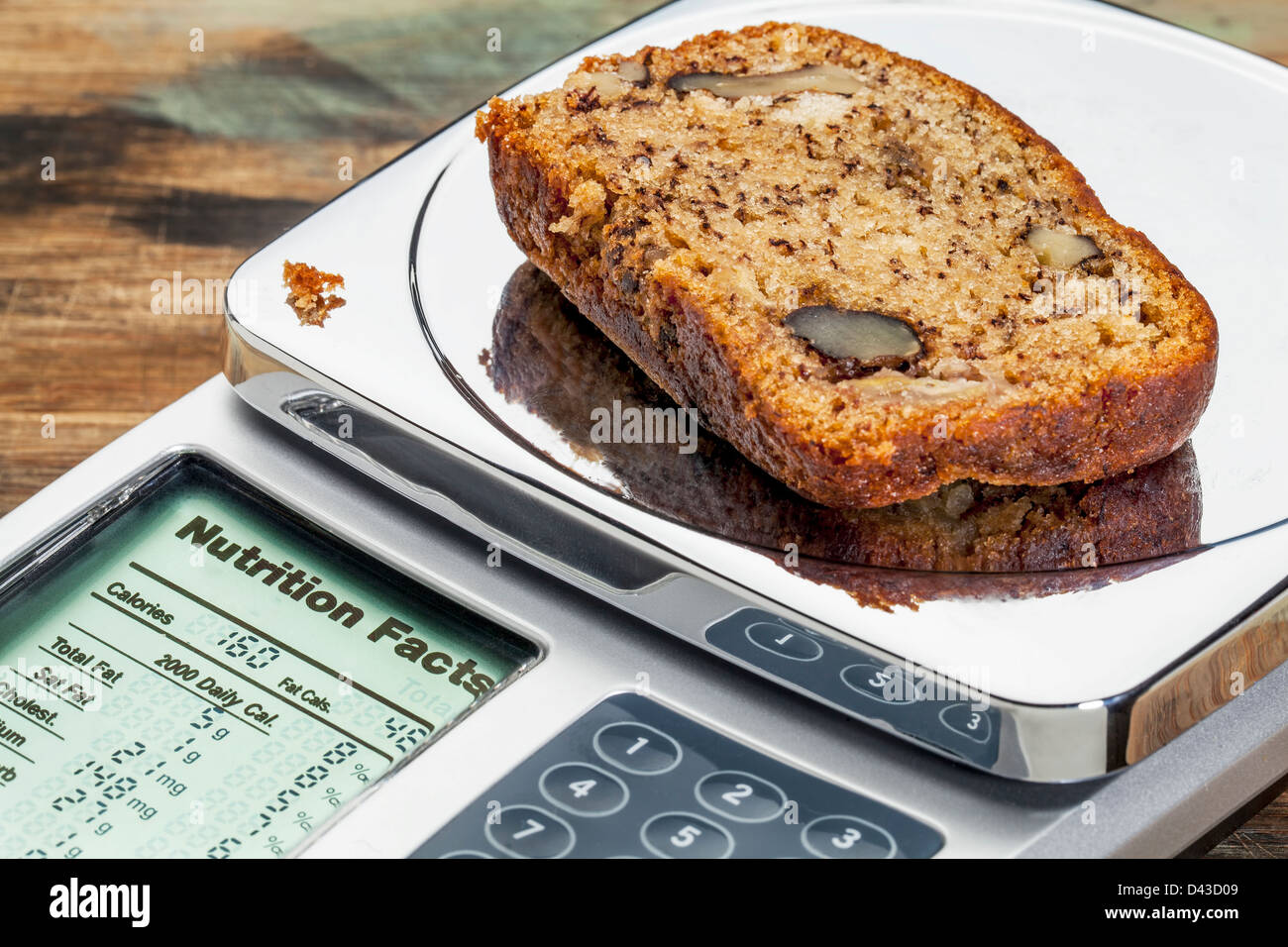 slice of banana bread with walnuts on diet scale displaying nutrition facts - a diet concept Stock Photo