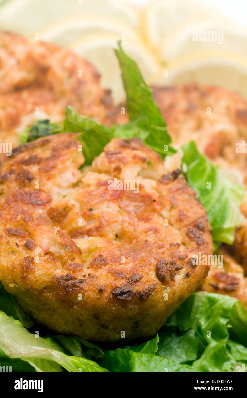 lobster cakes on bed of lettuce with lemon slice wedges Stock Photo