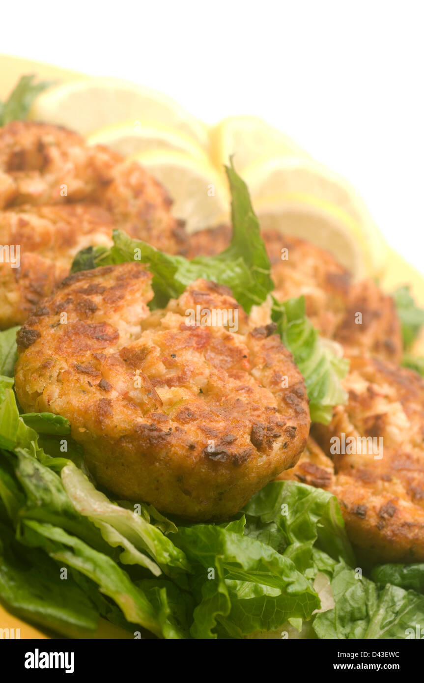 lobster cakes on bed of lettuce with lemon slice wedges Stock Photo
