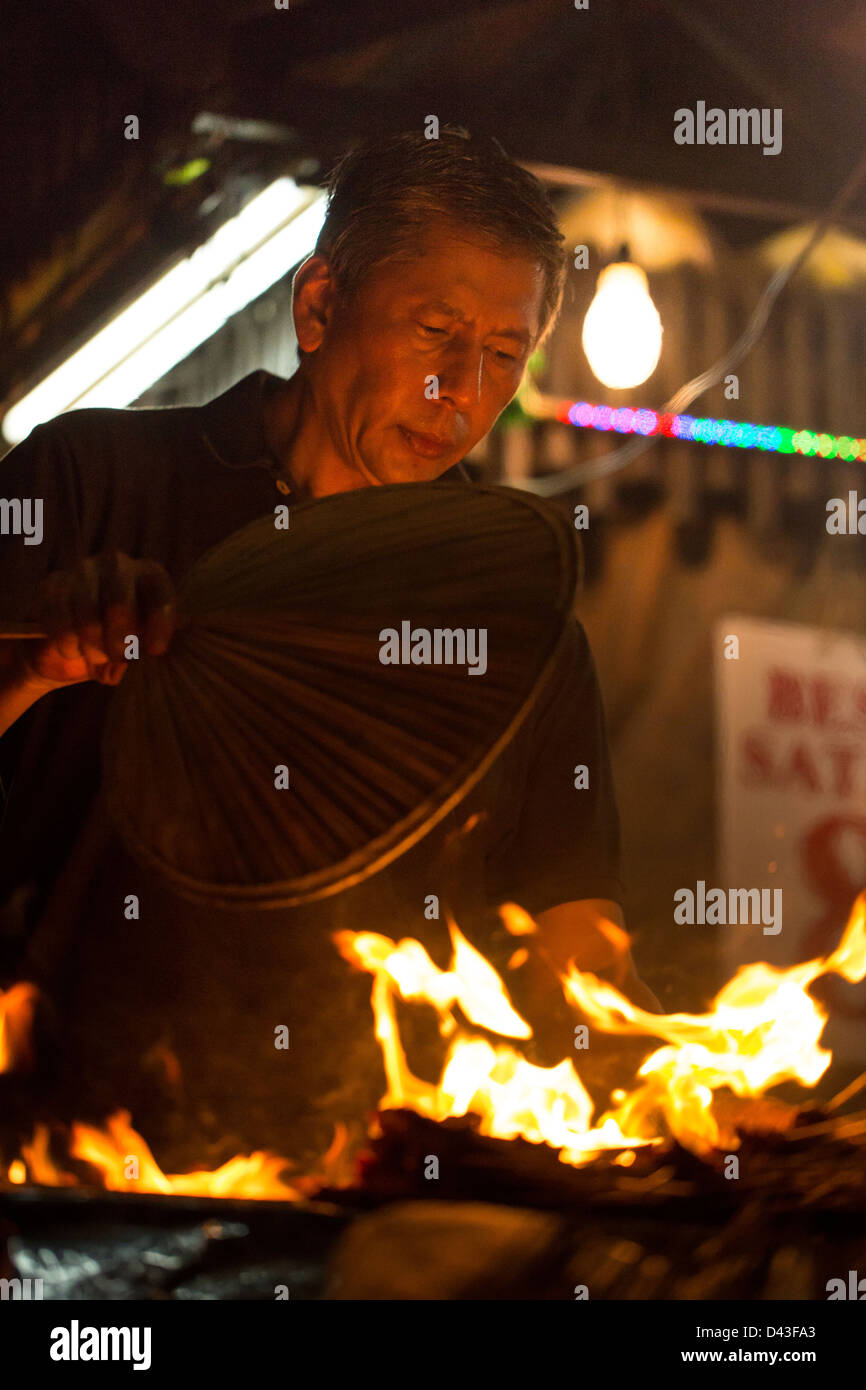 SINGAPORE - 2013:  Satay Street at Lau Pa Sat hawker food market. Satay chef fans his barbecue grill. Stock Photo