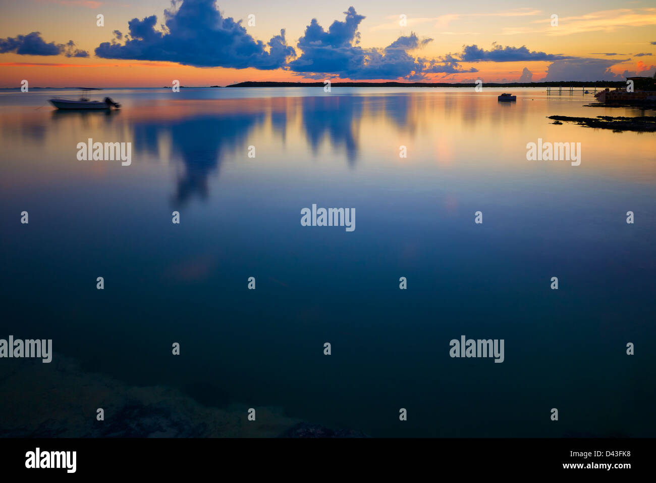 The water of a small bay in Exuma Island, Bahamas, falls totally still as the sun sets. Stock Photo