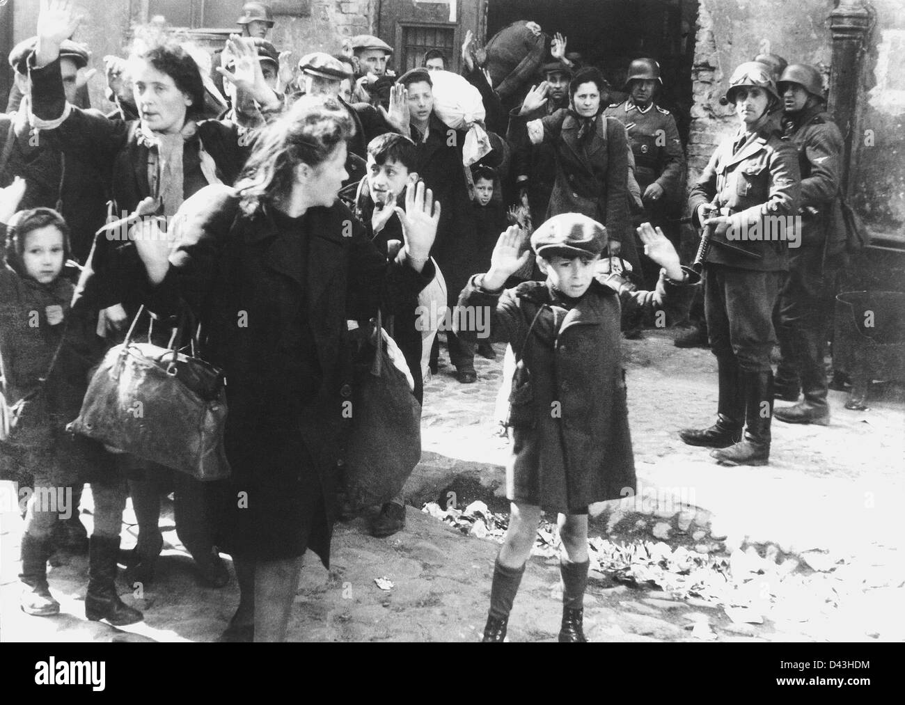 Jewish civilians are forcibly removed from the Warsaw ghetto by German SS soldiers during the uprising May 1943. People identified in the picture: Identity of the boy in the front was not confirmed, but is possibly Artur Dab Siemiatek, Levi Zelinwarger (next to his mother, Chana Zelinwarger) or Tsvi Nussbaum. Hanka Lamet - small girl on the left Matylda Lamet Goldfinger - Hanka's mother next to her (second from the left) Leo Kartuziński - teenaged boy in the background with white bag on his shoulder Golda Stavarowski -  SS man with gun, was executed in 1969 Stock Photo