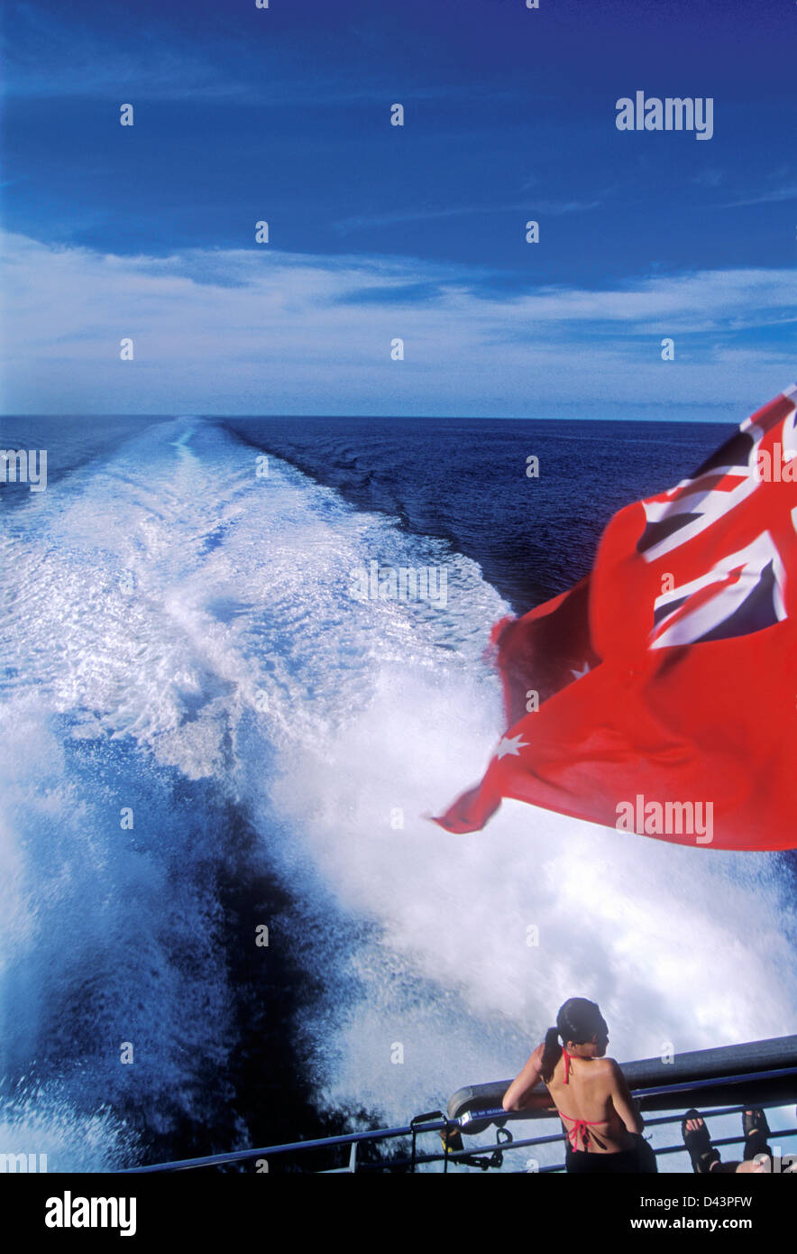 Ocean wake trails behind boat flying red Australian flag on the Great