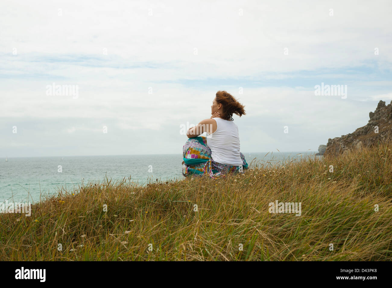 Woman Sitting and Looking into the Distance at the Beach, Camaret-sur-Mer, Crozon Peninsula, Finistere, Brittany, France Stock Photo
