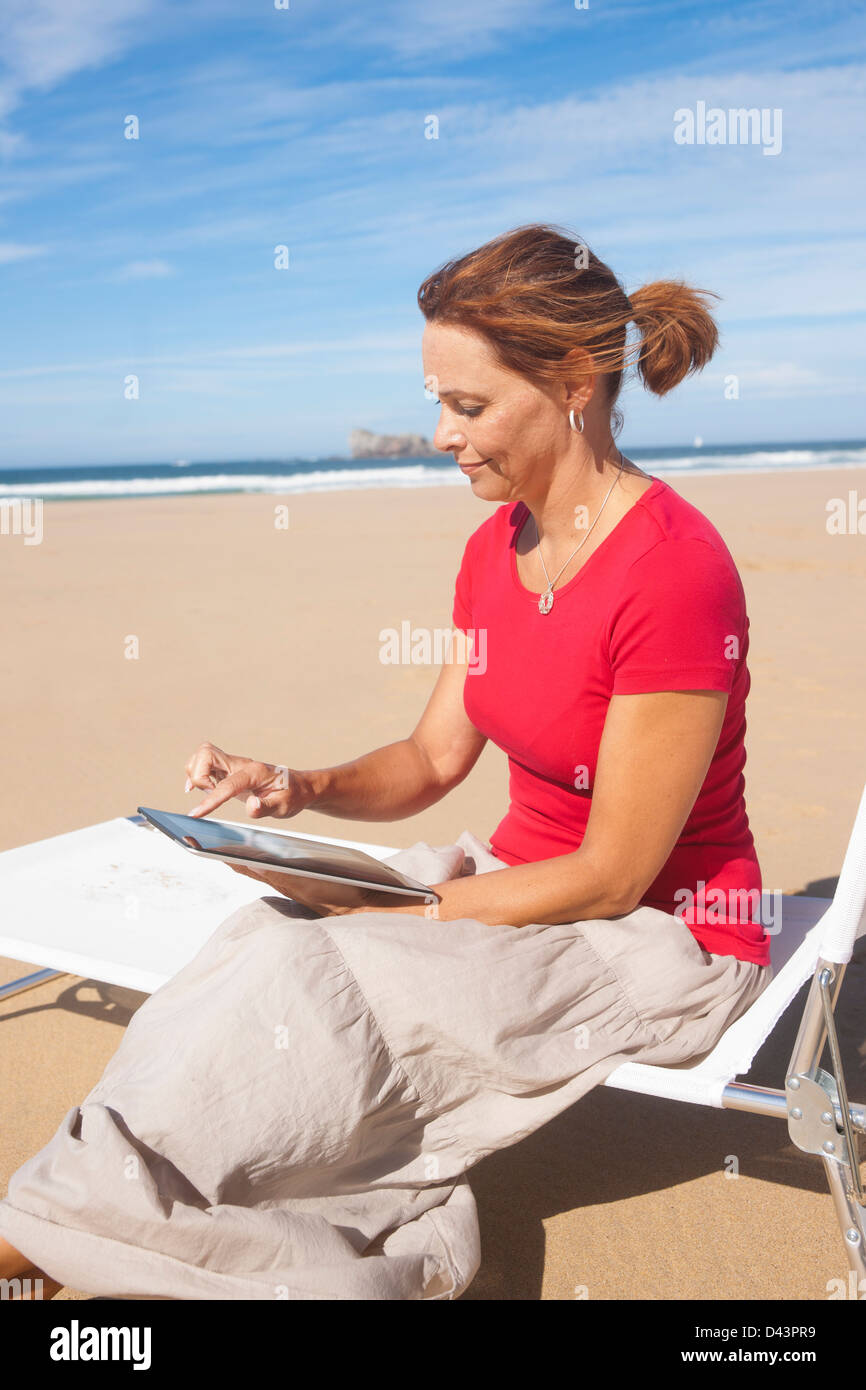 Woman Using Tablet at the Beach, Camaret-sur-Mer, Crozon Peninsula, Finistere, Brittany, France Stock Photo