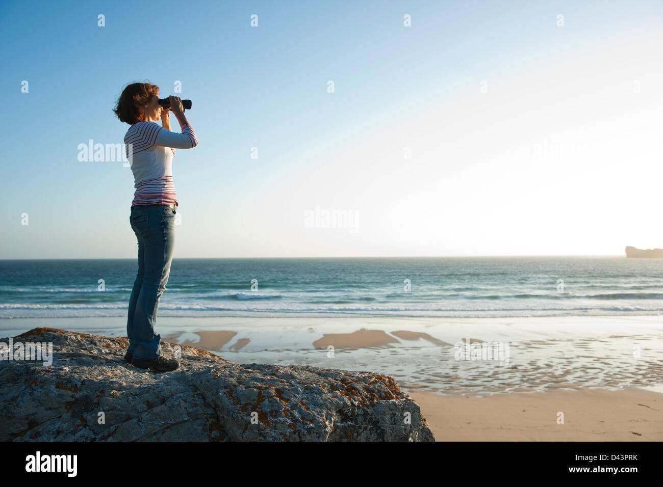 Woman Looking into the Distance Using Binoculars at the Beach, Camaret-sur-Mer, Crozon Peninsula, Finistere, Brittany, France Stock Photo