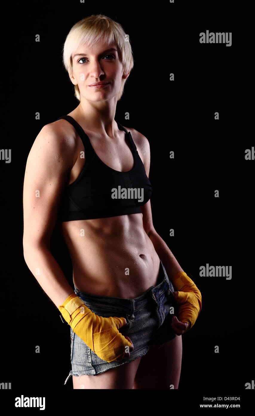 boxing young woman on black background in dramatic lighting Stock Photo