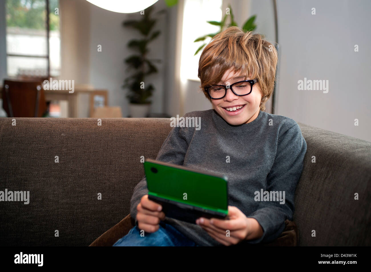 9 year old boy child playing with nintendo ds on the coach in the living  room at home Stock Photo - Alamy