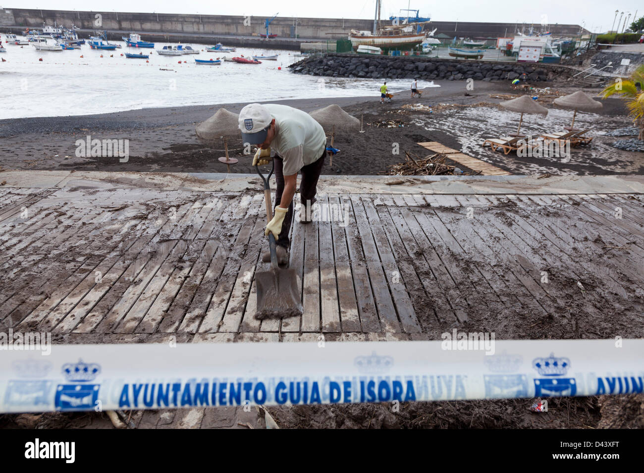Cleaning up after storm damage in Playa de San Juan, Guia de Isora, Tenerife, Canary Islands. Winds of up to 100 km/hour and extremely high rainfall caused flooding bringing lots of mud and other debris on to the beach promenade and walkways of San Juan. Stock Photo