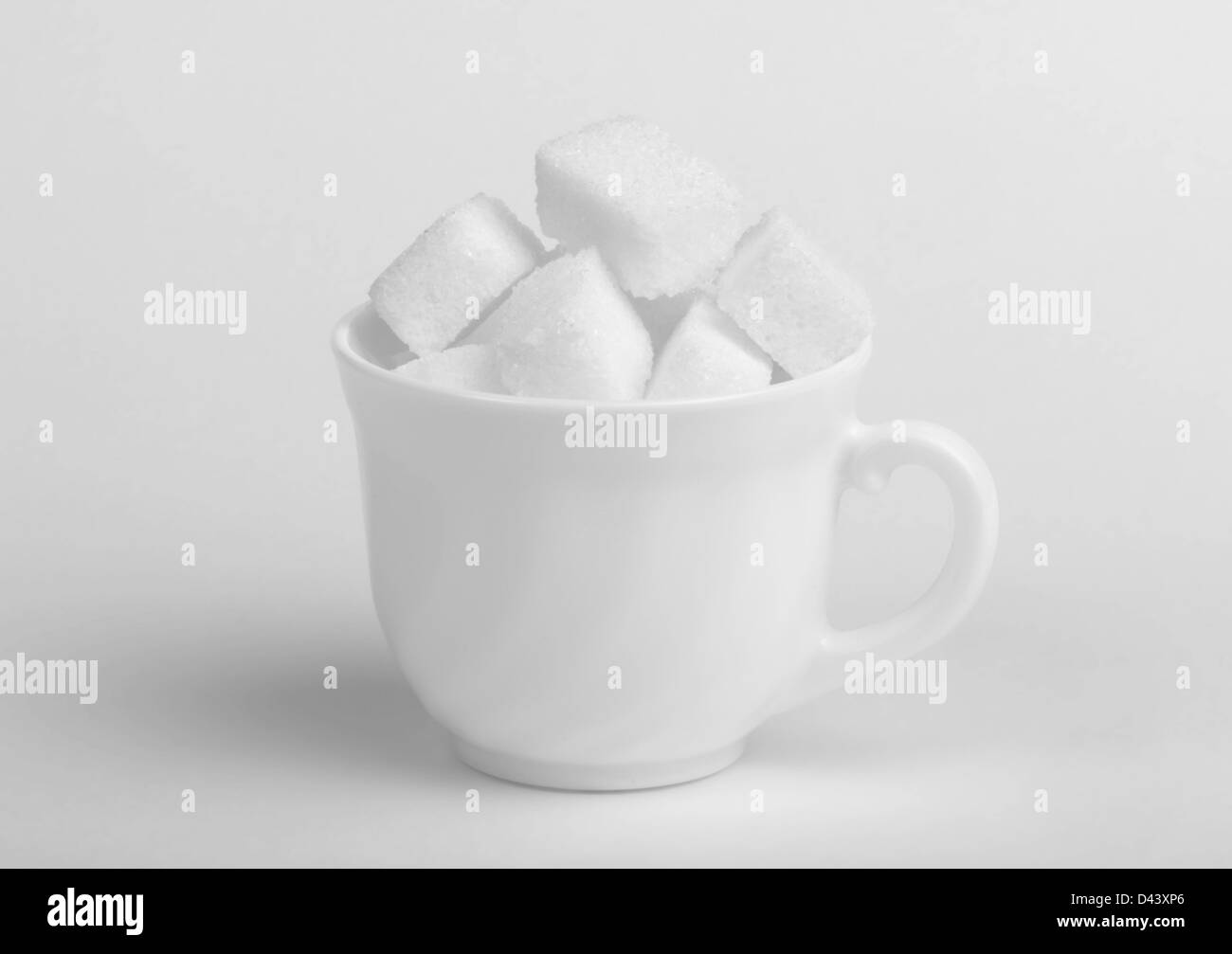 Sugar lumps in cup on white background Stock Photo