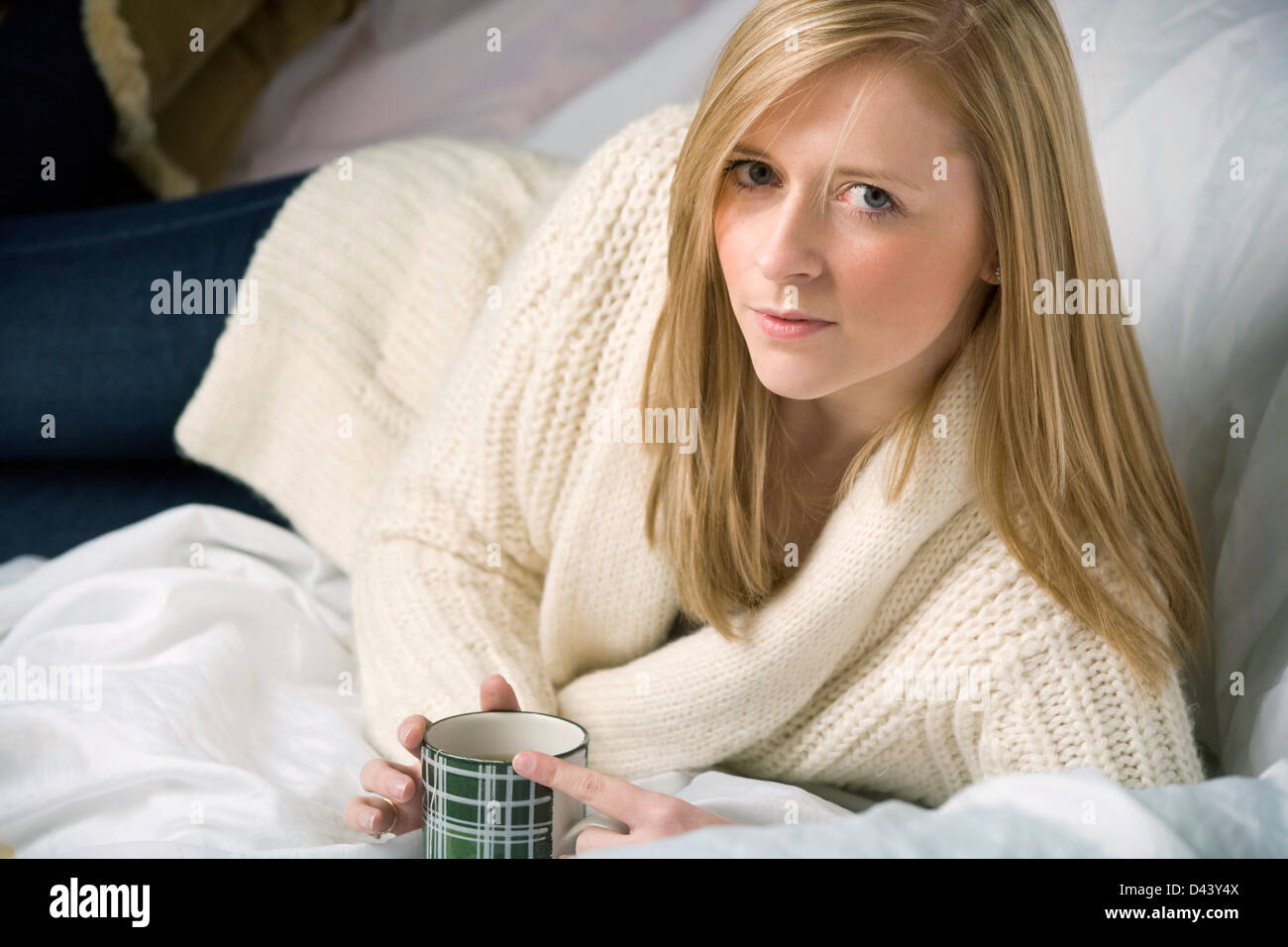 Young blonde woman relaxing with a cup of tea on a sofa Stock Photo - Alamy