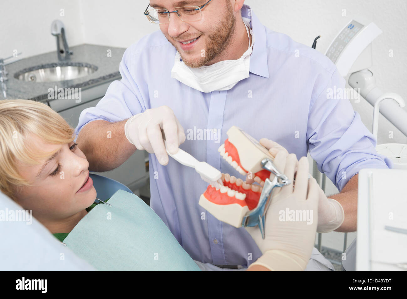 Dentist demonstrating to Boy how to Brush Teeth during Appointment, Germany Stock Photo