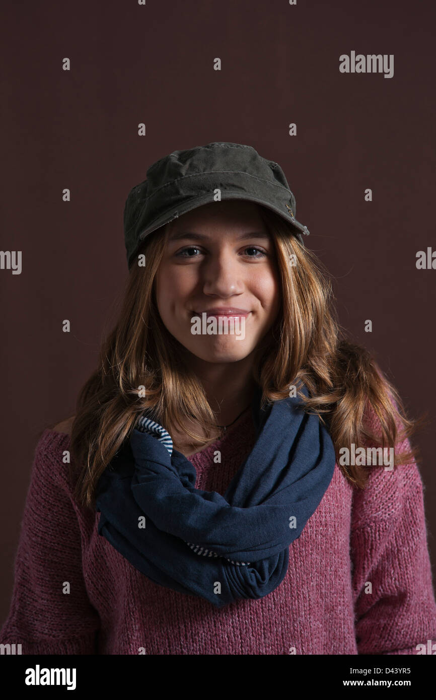 Portrait of Teenage Girl Smiling at Camera, wearing Baseball Hat and Scarf, Studio Shot on Black Background Stock Photo