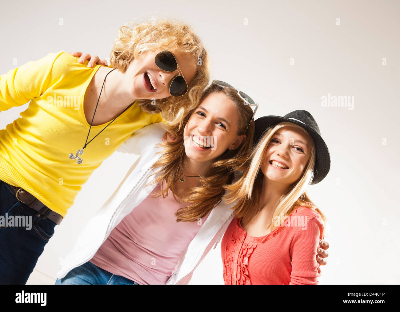 Portrait of Three, Cool Teenage Girls, Looking at Camera Smiling, Diagonal Studio Shot on White Background Stock Photo