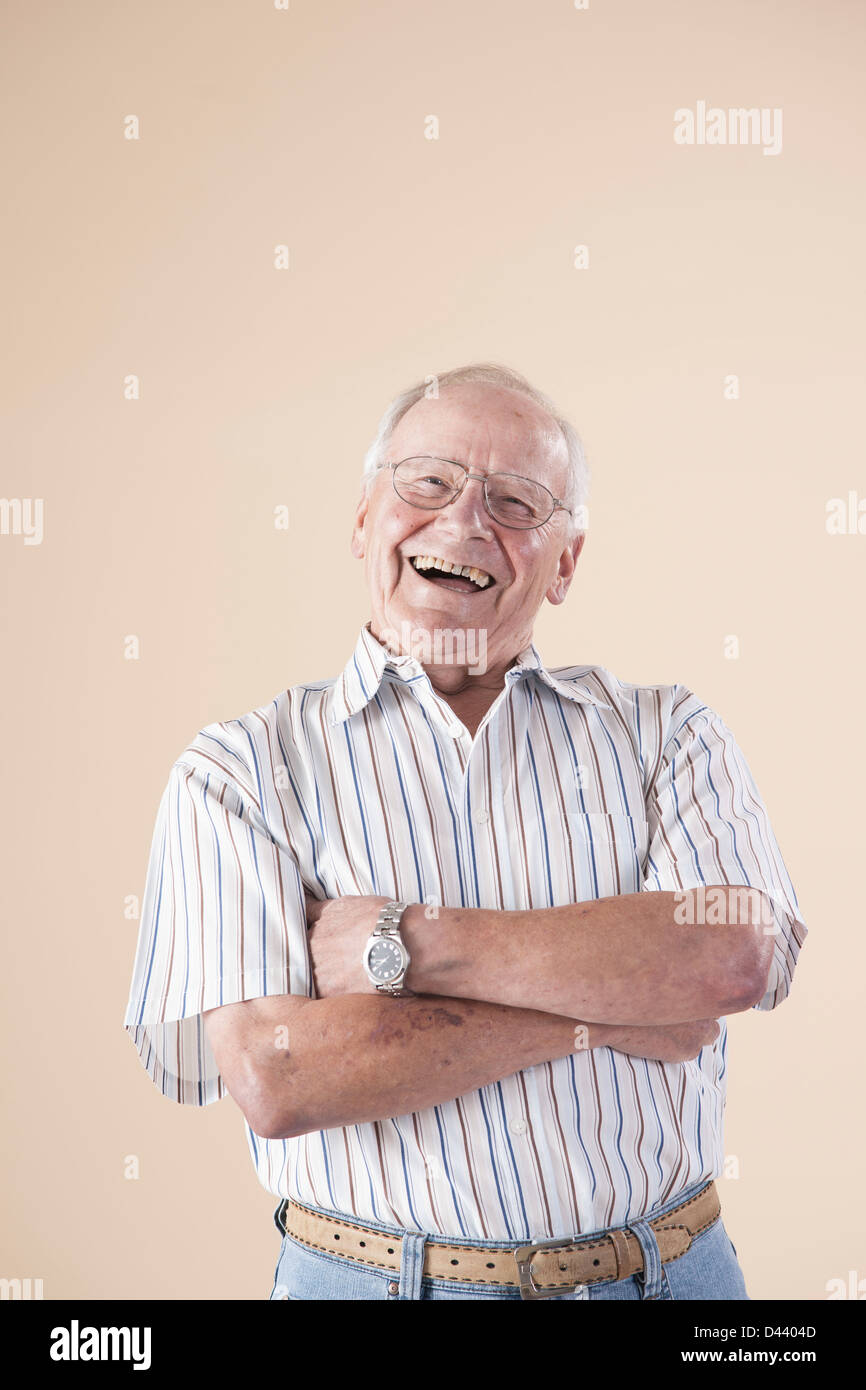 Portrait of Senior Man wearing Aviator Eyeglasses, Looking at Camera Laughing, in Studio on Beige Background Stock Photo