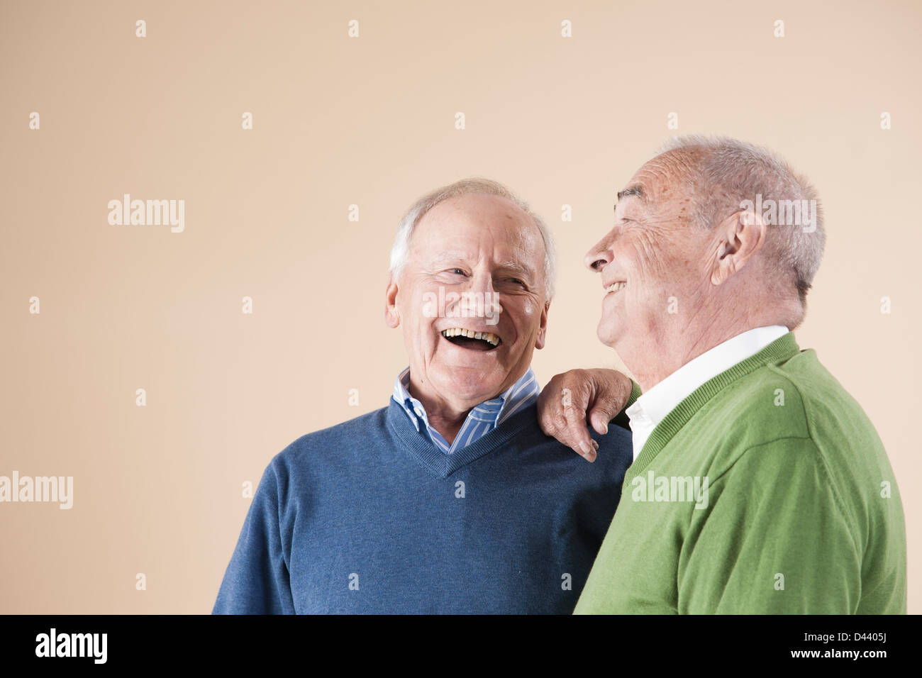 Portrait of Two Senior Men Laughing Together, Studio Shot on Beige Background Stock Photo