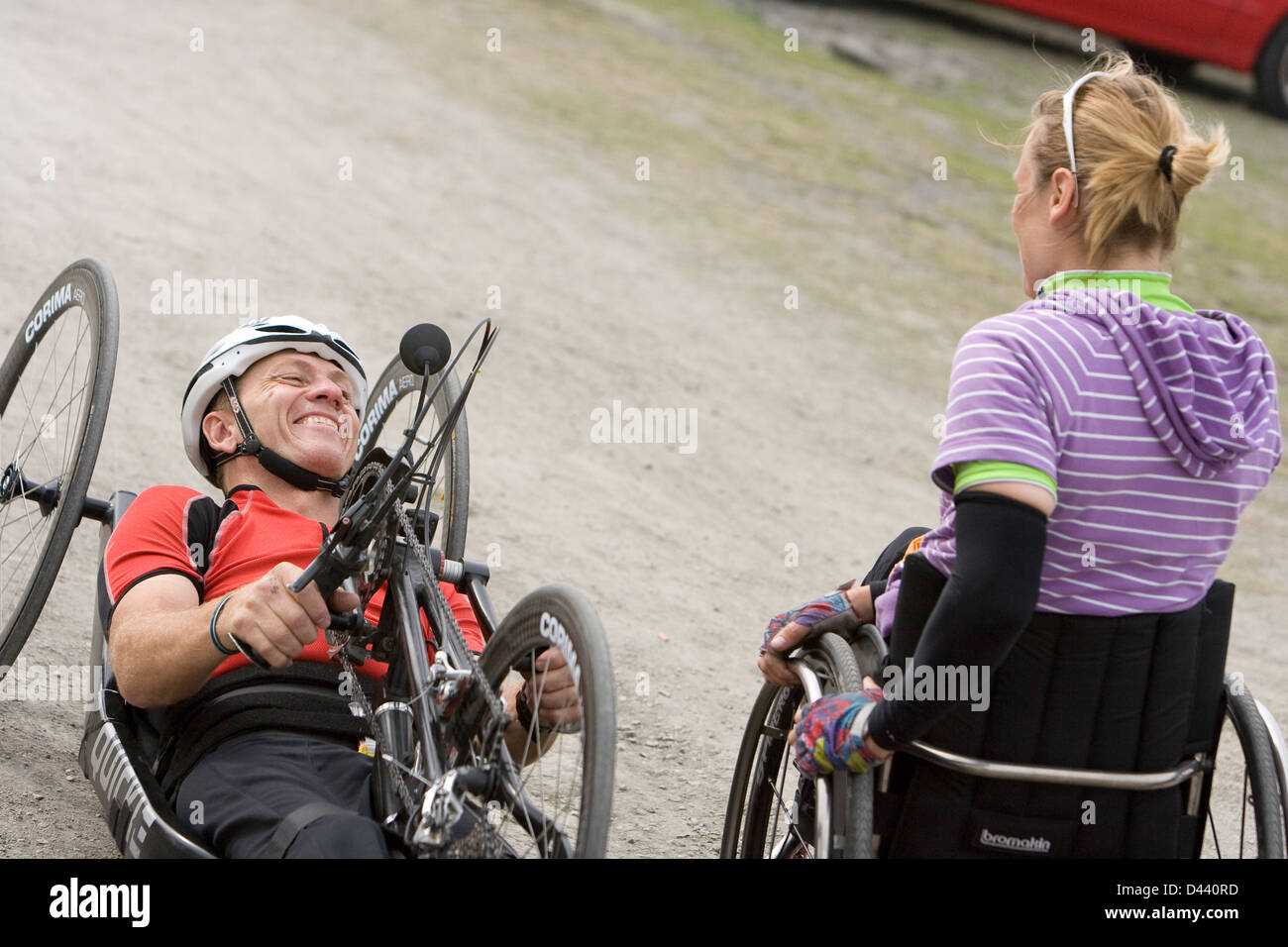 Man riding recumbent bike laughing with woman wheelchair user Stock