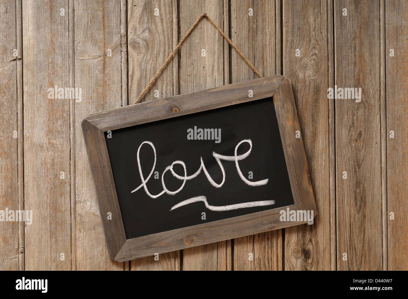 Love Written in Cursive on Chalkboard and Hanging on Wooden Wall Stock
