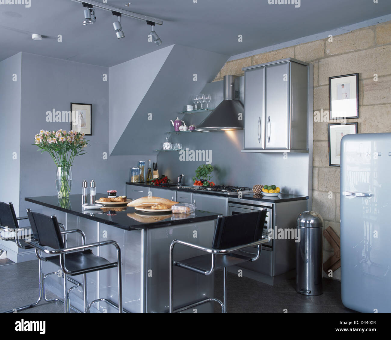 Leather+chrome stools at breakfast bar with black granite worktop in modern kitchen with Smeg
