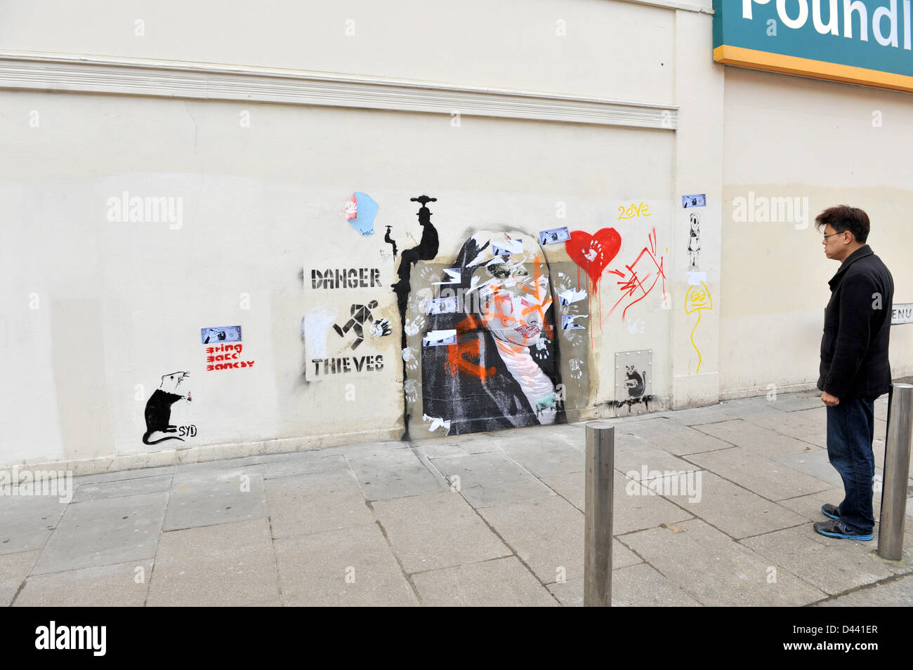 Wood Green London UK. 4th March 2013. A man looks at the new Banksy syle rat added to the graffiti on the wall of Poundland. The words Bring back Banksy and a