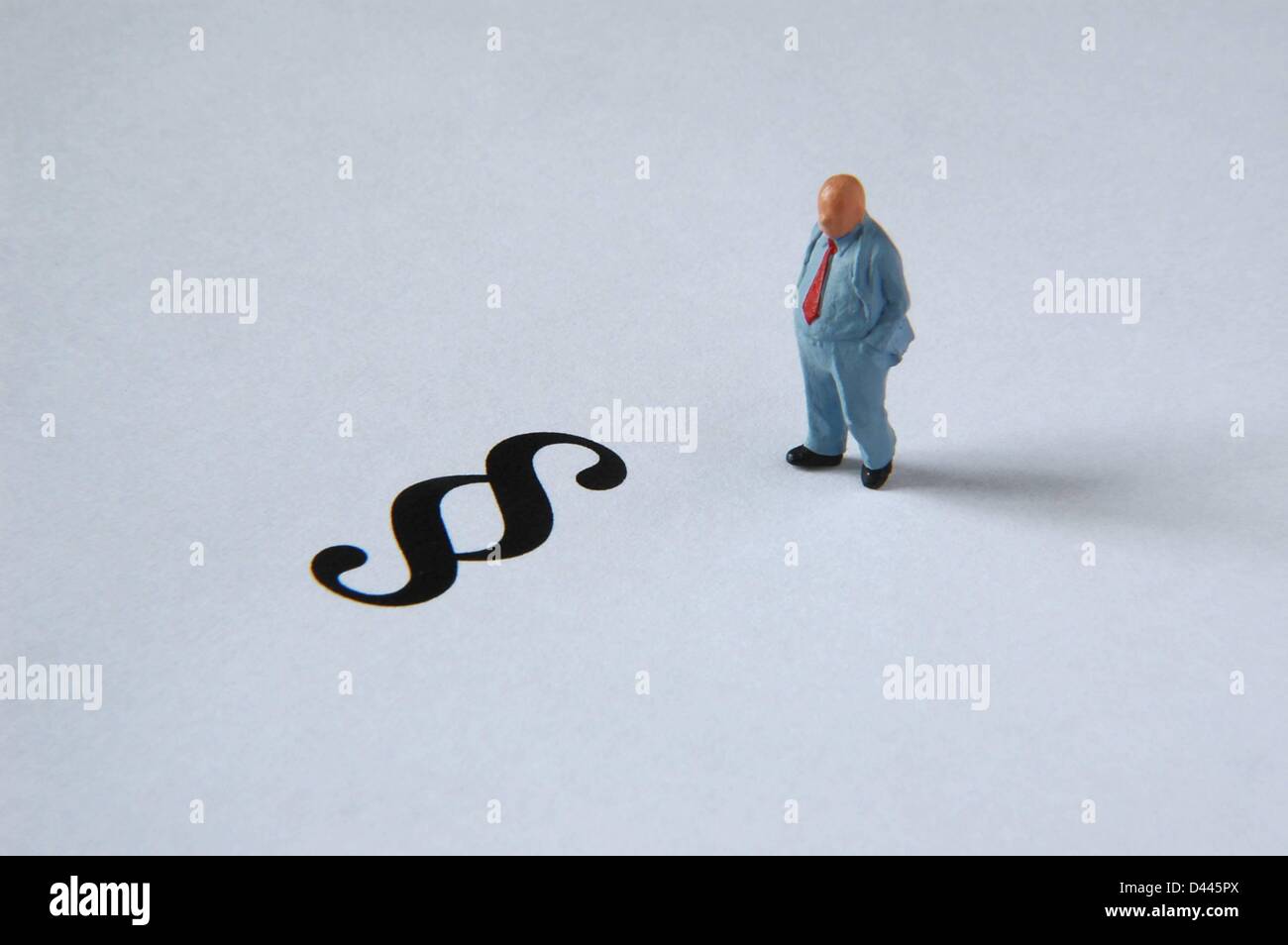 Illustration - A miniature figure in a suit stands next to the paragraph sign in Berlin, Germany, 5 December 2007. Fotoarchiv für ZeitgeschichteS.Steinach Stock Photo