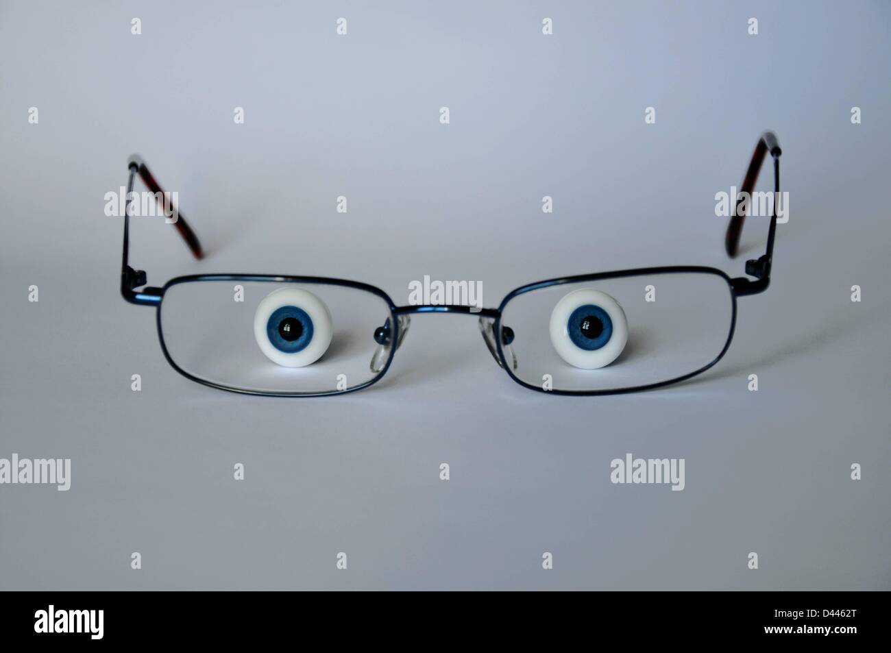 Illustration - Two glass eyes are pictured on a table looking through glasses in Berlin, Germany, 3 June 2011. Fotoarchiv für ZeitgeschichteS.Steinach Stock Photo