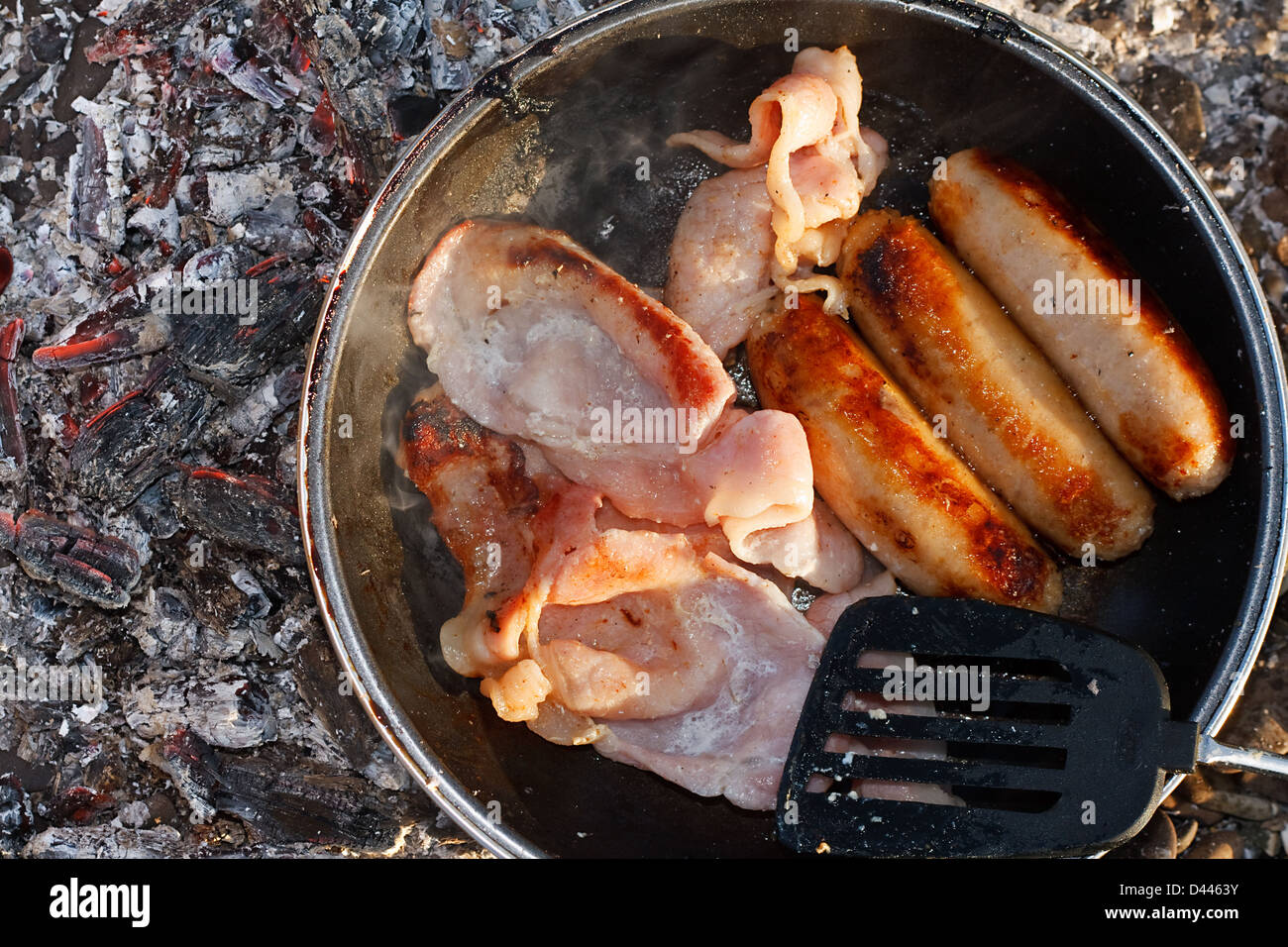 Camp cooking on the embers of an open fire known as a cook out Stock Photo